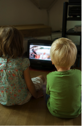 Photo of a young girl and boy watching a portable television.