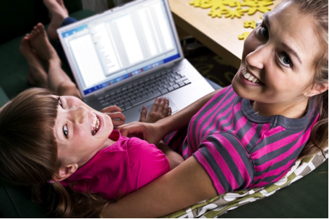 Photo of a girl and a young woman using a laptop computer.
